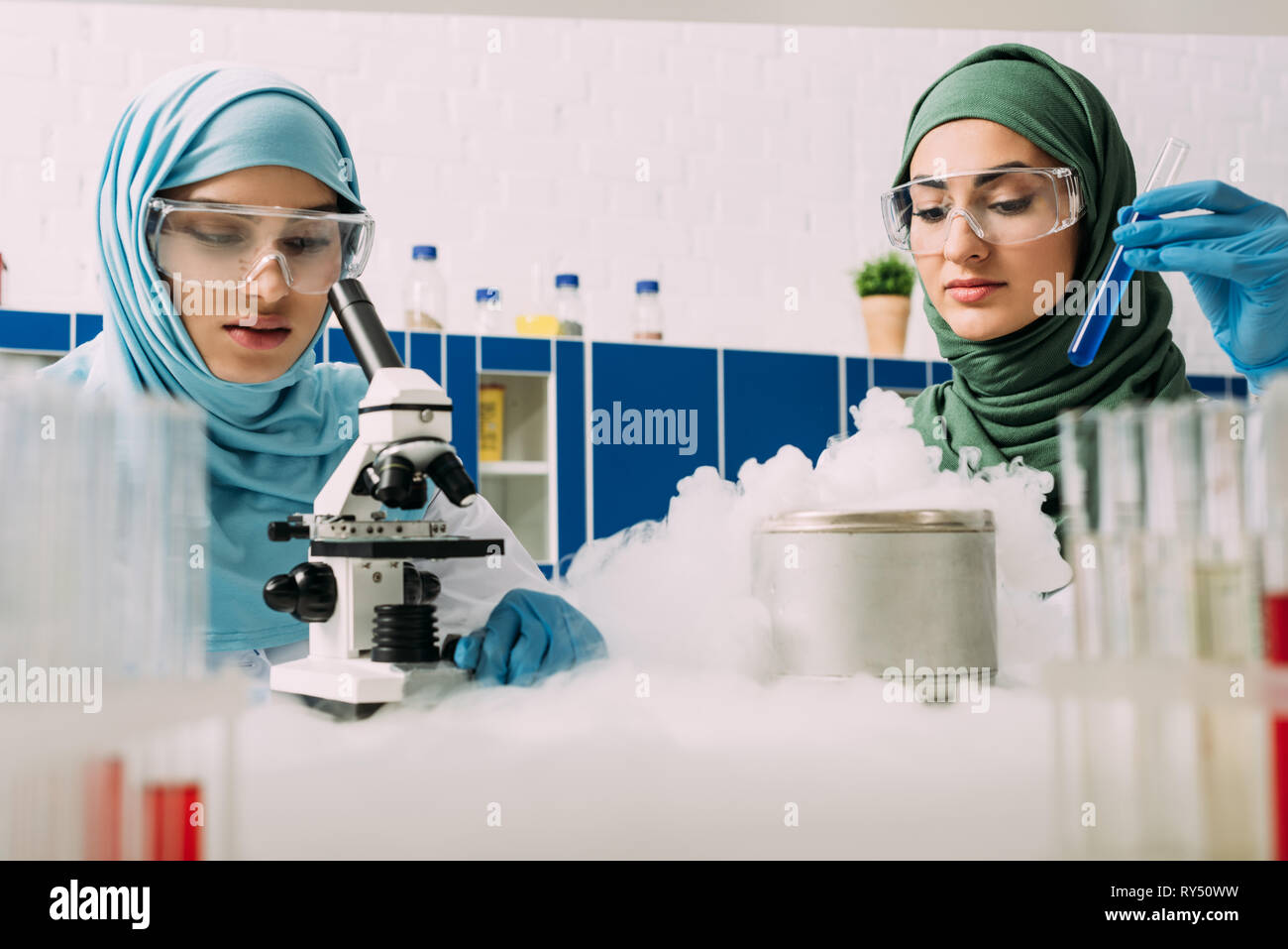 female muslim scientists experimenting with microscope, test tube and