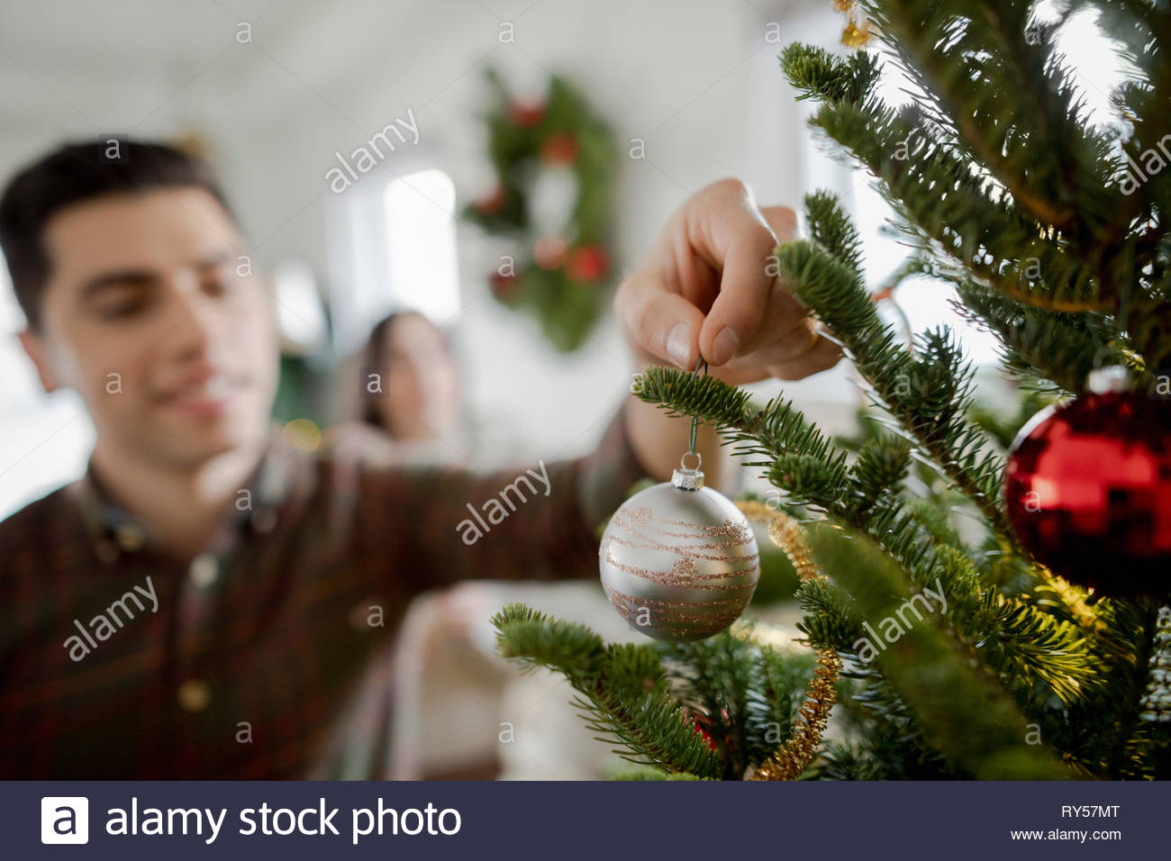 Young man hanging ornament on christmas tree Stock Photo