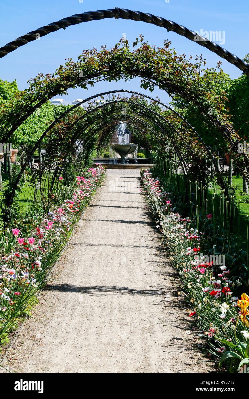 An arched pathway lined with flowers at Bangor Castle Walled Garden in Northern Ireland Stock Photo