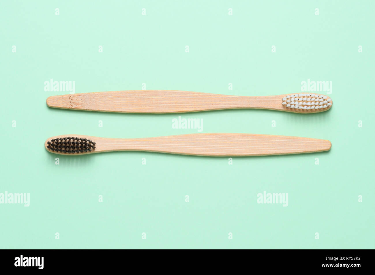 Bamboo toothbrushes on light green background top view Stock Photo
