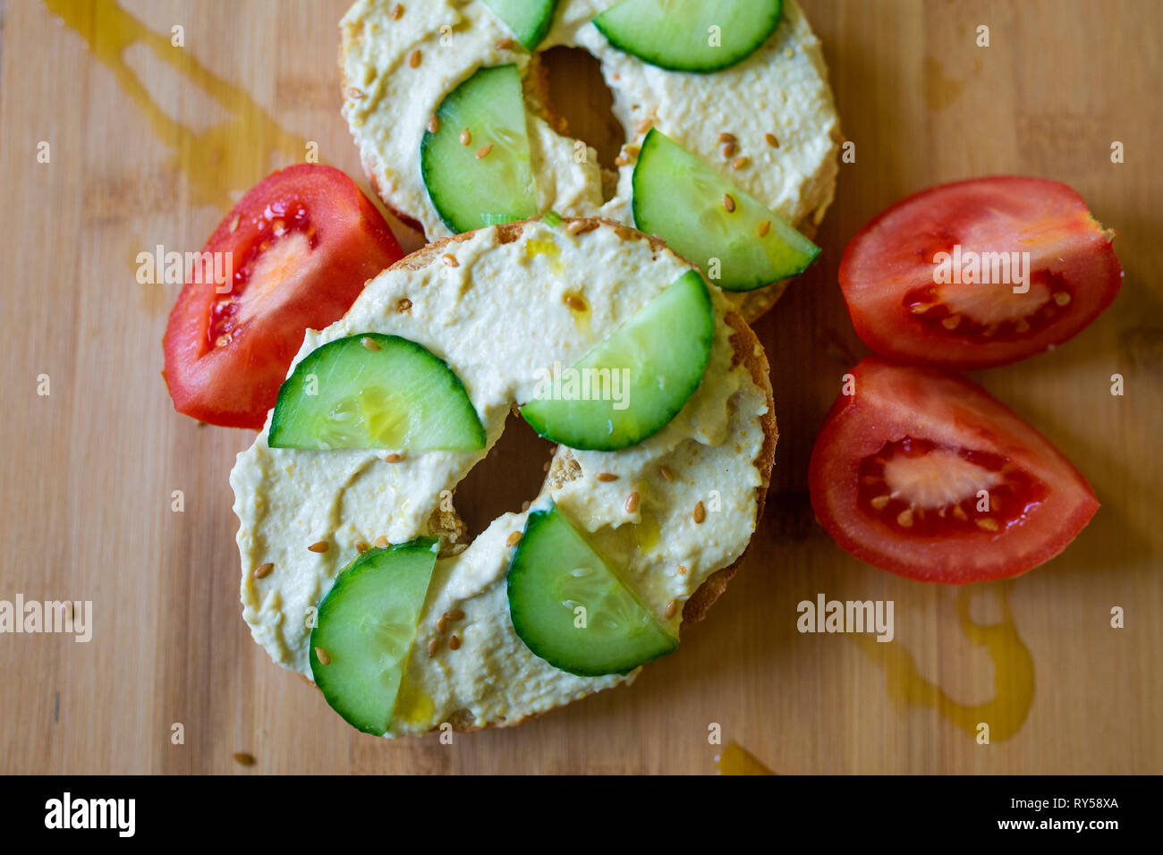 Vegan food. A bagel with hummus, humous, hommous and cucumber, vegan, vegetarian, healthy food breakfast or lunch on a wooden board Stock Photo