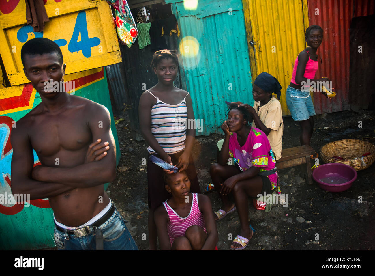 Young Haitian girls and women style their hair on the street inside a shanty town in Port-au-Prince, Haiti. Stock Photo