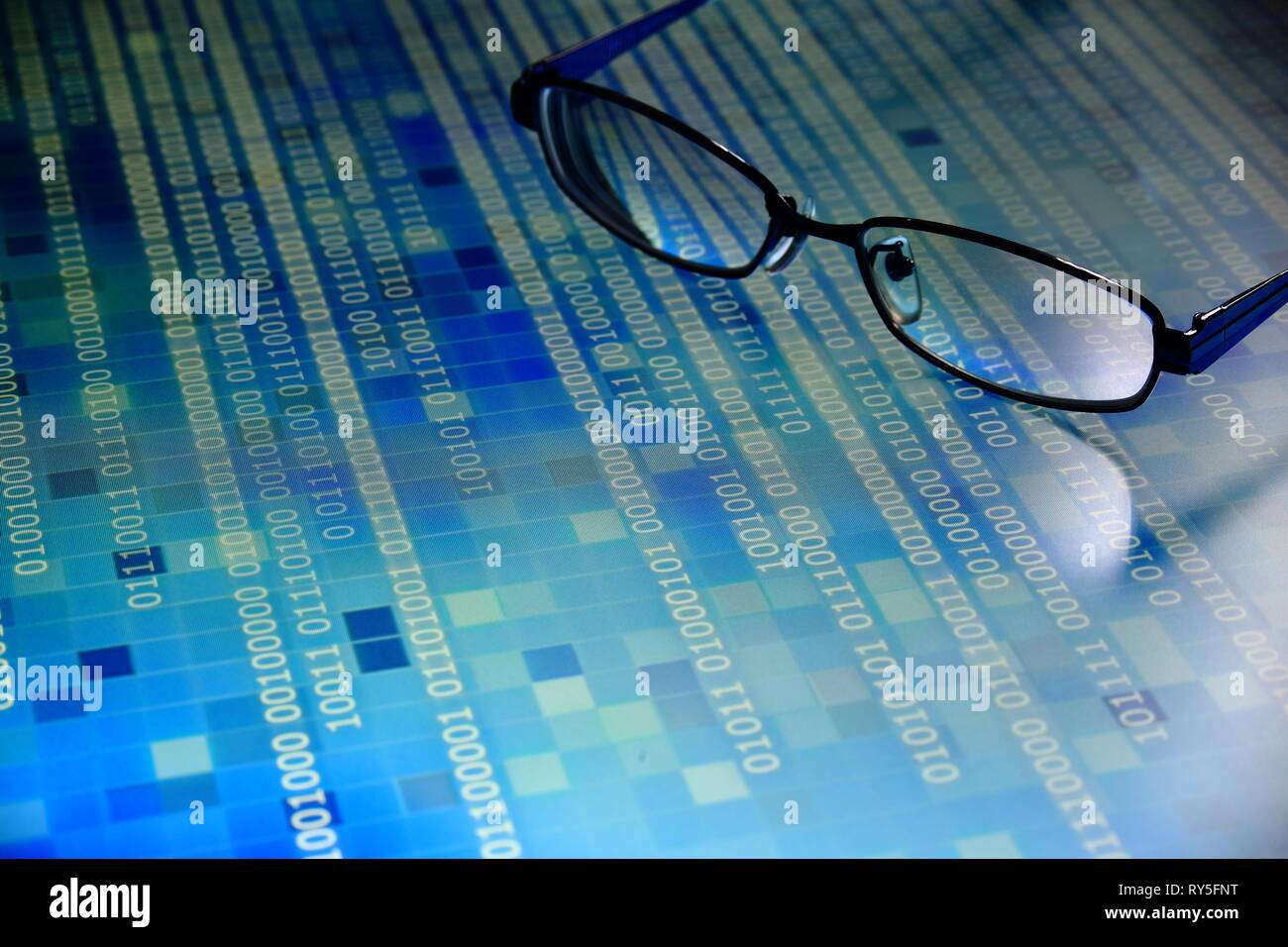 big data analysis. blue binary code on led panel with black background and glasses placed over the information panel. hacker and source code analysis. Stock Photo