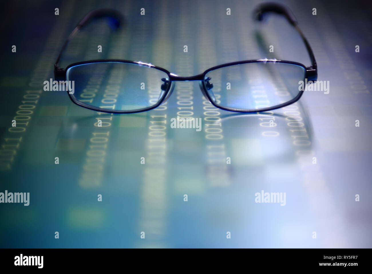 big data analysis. blue binary code on led panel with black background and glasses placed over the information panel. hacker and source code analysis. Stock Photo