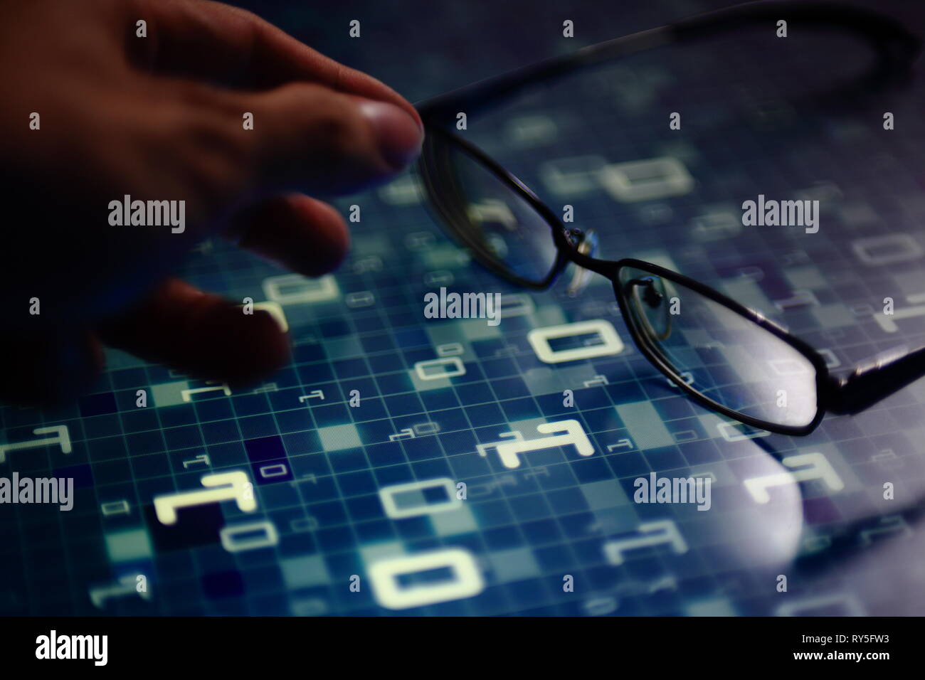 hand reaching for glasses on digital led displaying multiple layers of binary code computer data matrix. big data analytics and digital language conce Stock Photo
