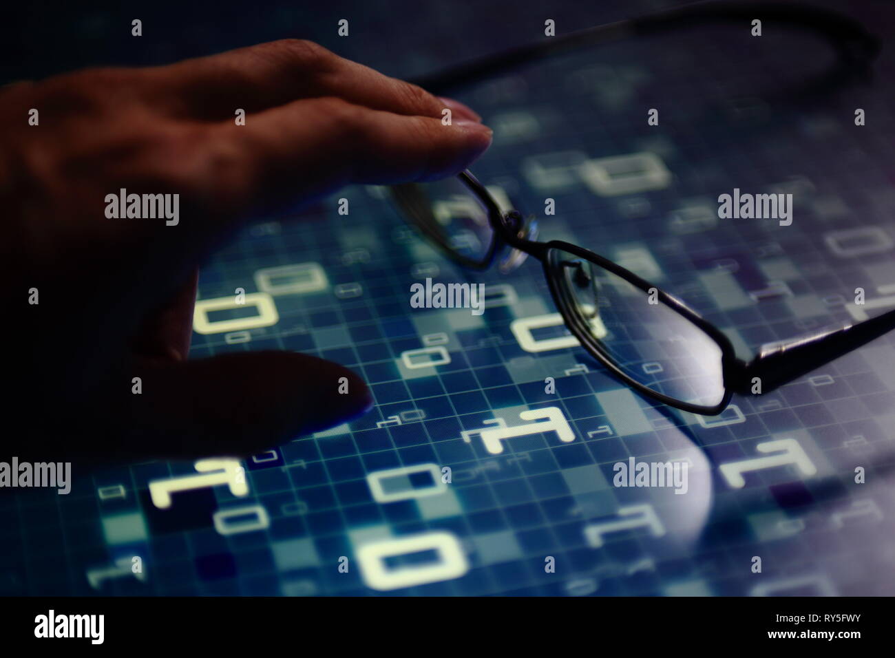 hand reaching for glasses on digital led displaying multiple layers of binary code computer data matrix. big data analytics and digital language conce Stock Photo
