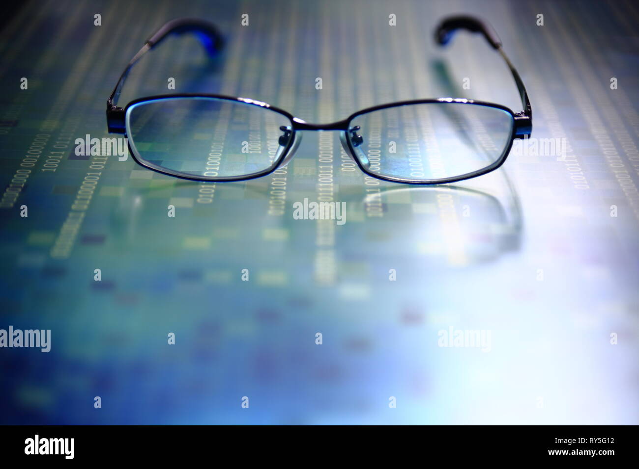 big data analysis. glasses placed on a LED digital panel display white light one and zero binary text number in moving motion pattern. modern technolo Stock Photo
