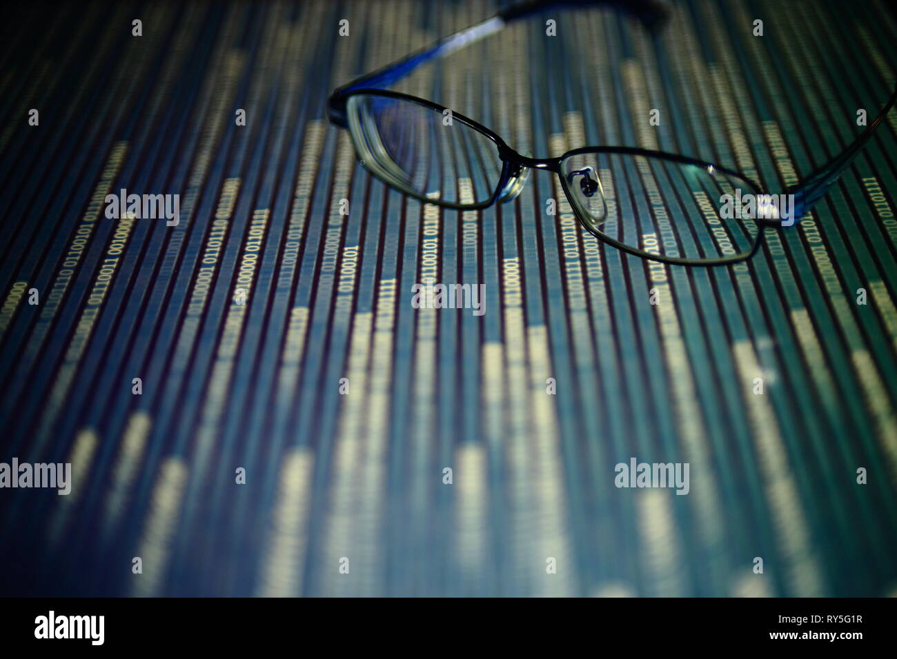 big data analysis. glasses placed on a LED digital panel display white light one and zero binary text number in moving motion pattern. modern technolo Stock Photo