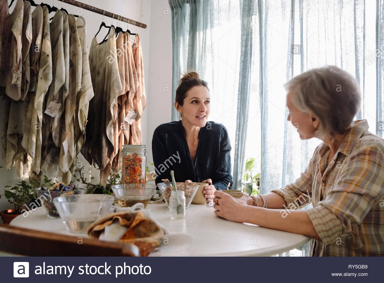 Female artists dyeing clothing with dried flowers, taking a coffee break Stock Photo