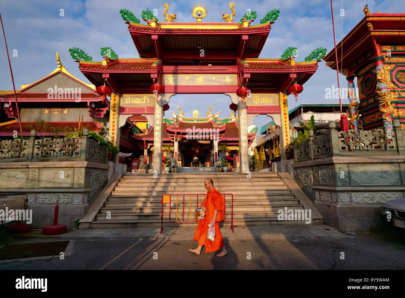 A Buddhist monk in Phuket Town, Thailand, during his morning alms' round passing the Taoist Jui Tui Temple Stock Photo