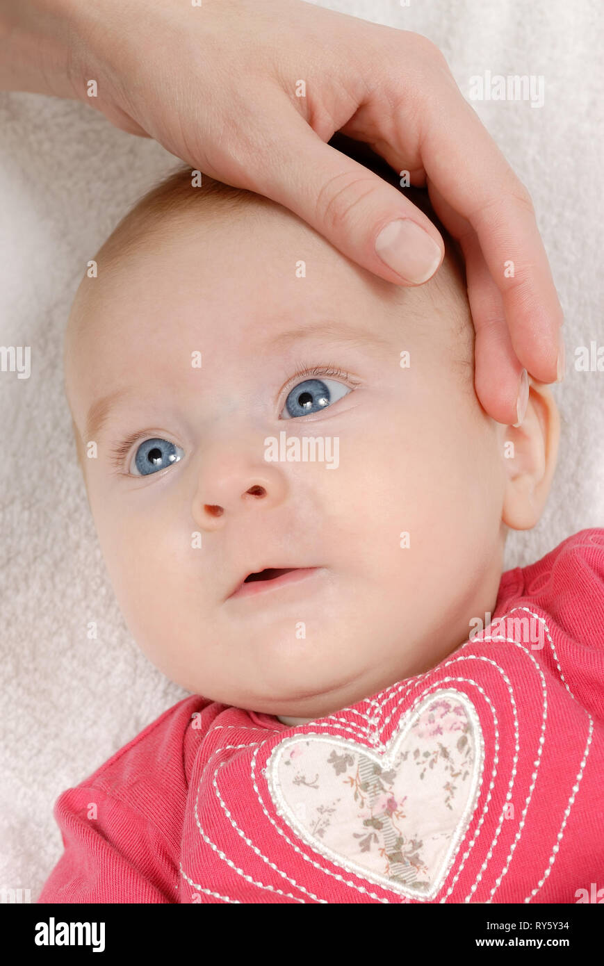 Cute newborn, baby girl lying on a white blanket and her mother's hand Stock Photo