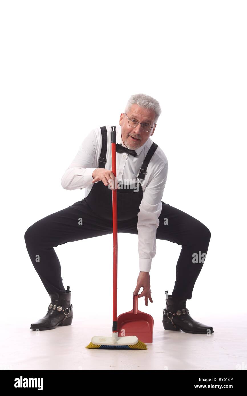 Grayhaired cleaner, janitor in a black jumpsuit with a mop and dustpan provides cleaning