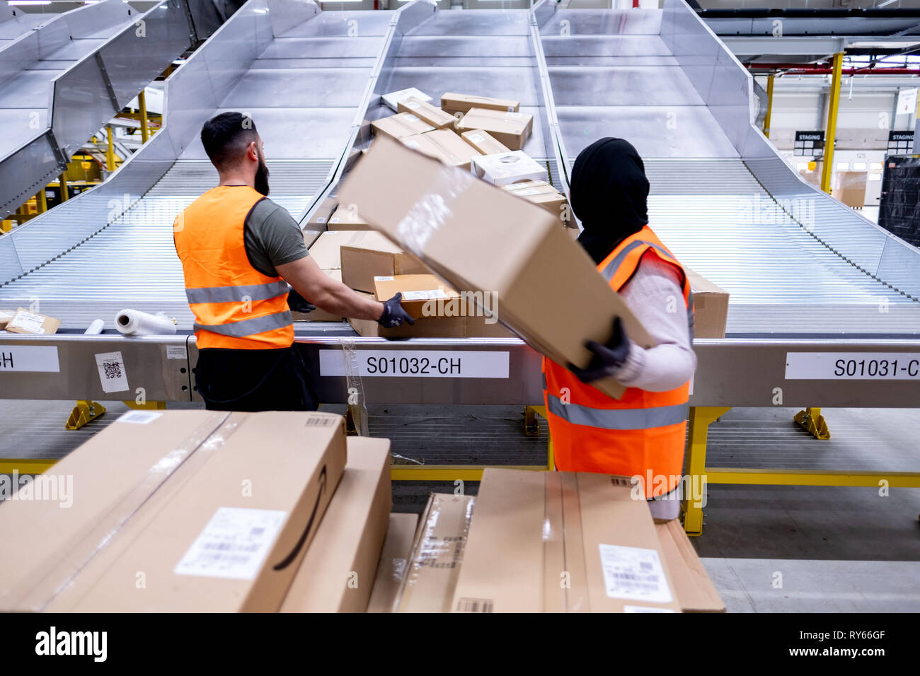 12 March 2019, Lower Saxony, Garbsen: Employees of the parcel shipper Amazon sort parcels at the sorting centre in Garbsen. Amazon sorts the parcels in Garbsen by delivery area and then forwards them to parcel shippers. Amazon already operates a logistics centre in Winsen in Lower Saxony. 700 jobs are to be created in Garbsen near Hanover. Photo: Peter Steffen/dpa Stock Photo