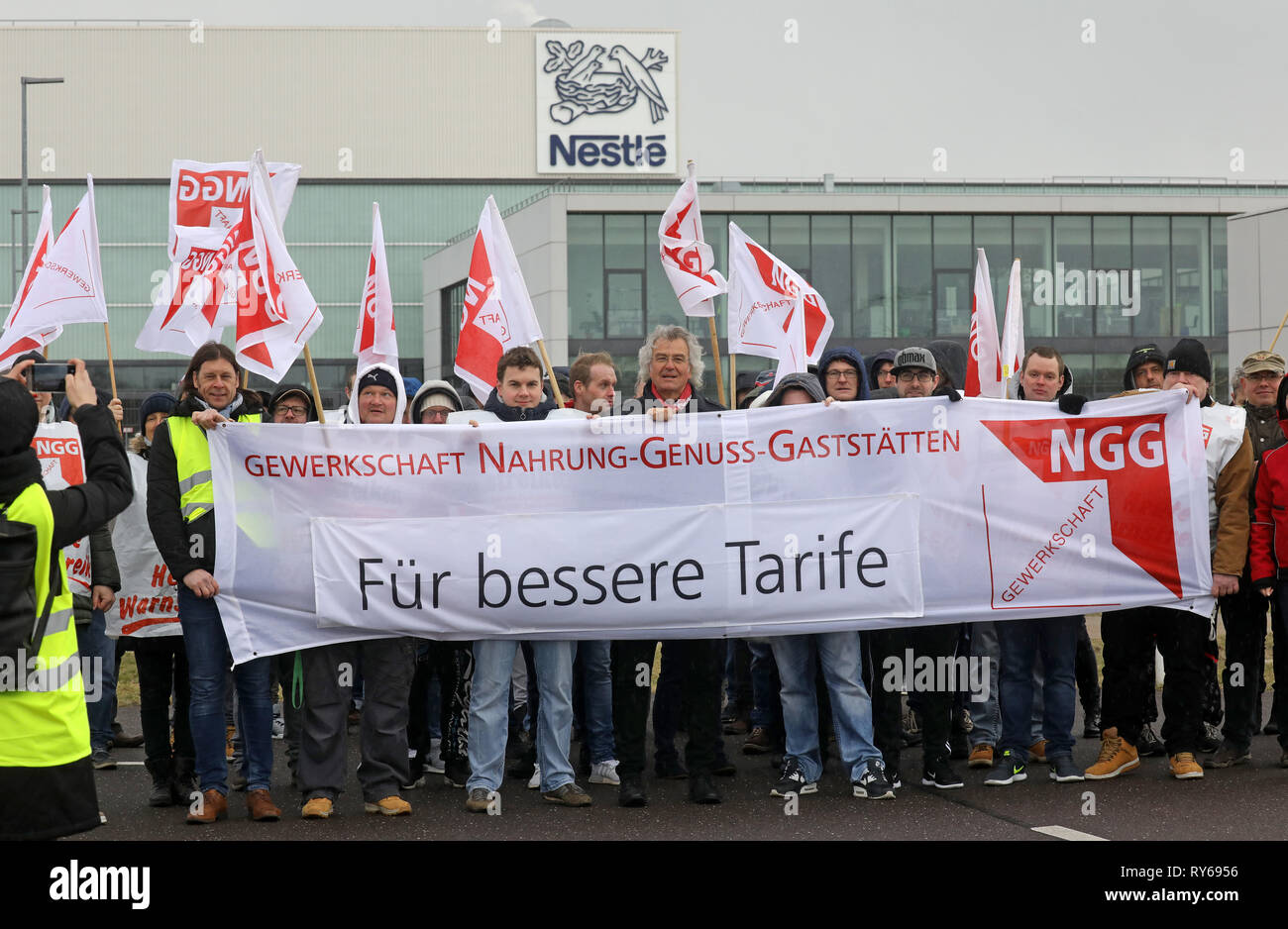 Schwerin, Germany. 12th Mar, 2019. Employees of Nestlé S.A. take part in a  four-hour warning strike with a poster "For better tariffs". The action is  part of a series of warning strikes