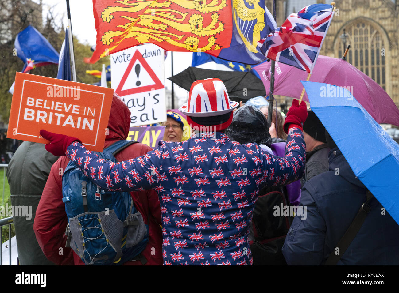 London, UK. 12th Mar, 2019. An anti-Brexit remain protestor wave flag and holds the banner 'Believe in Britain' outside The Houses of Parliament in London. Credit: AndKa/Alamy Live News Stock Photo