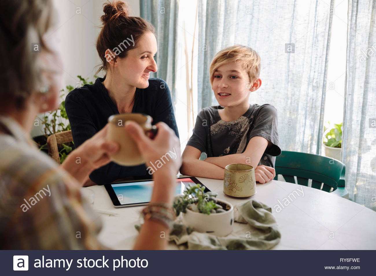 Multi-generation family talking at kitchen table Stock Photo