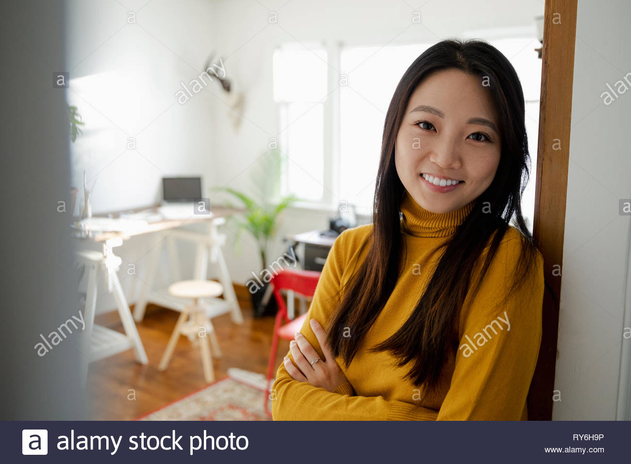 Portrait smiling, confident young woman standing in home office doorway Stock Photo