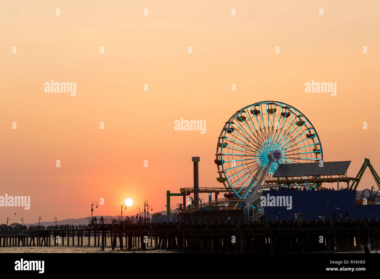 Silhouette pier over sea against clear orange sky during sunset Stock Photo