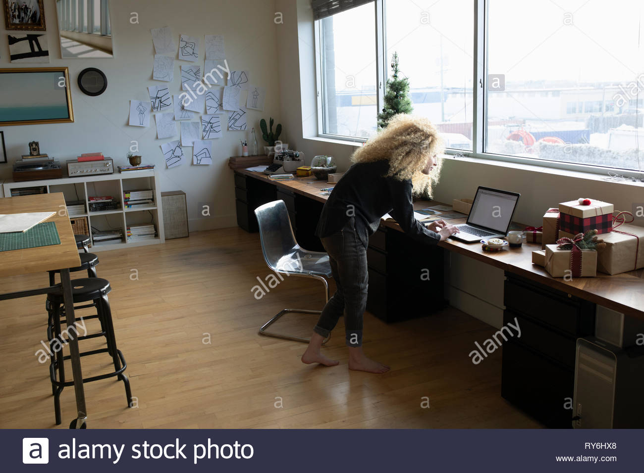 Young woman with blonde curly hair working at laptop in studio Stock Photo