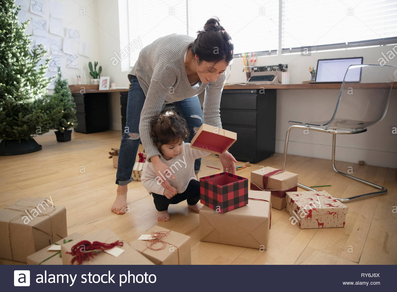 Latina mother and toddler daughter wrapping christmas gifts Stock Photo