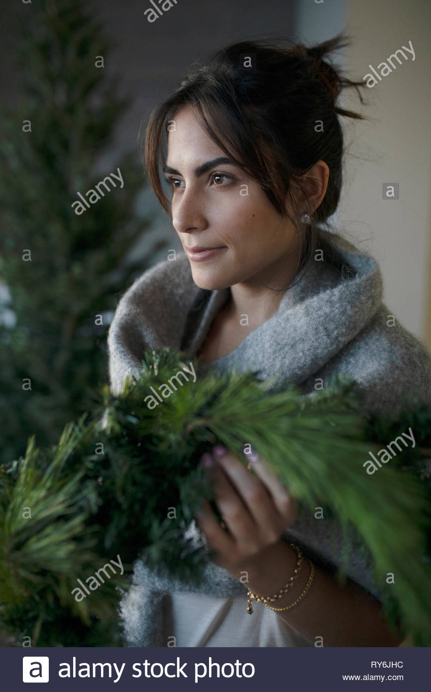 Serene young Latina woman holding christmas wreath Stock Photo