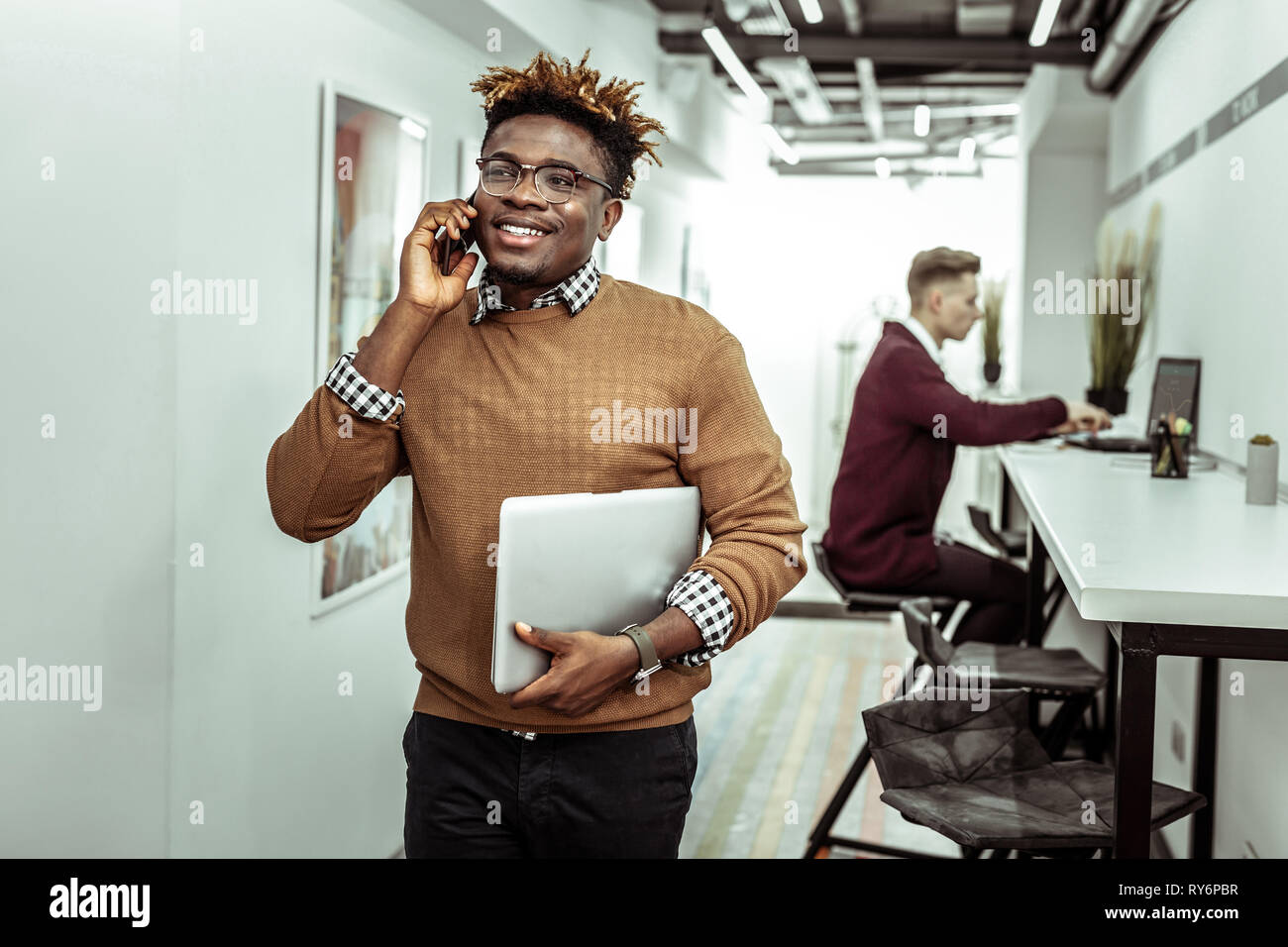 Beaming Guy In Clear Glasses With Dreadlocks Having