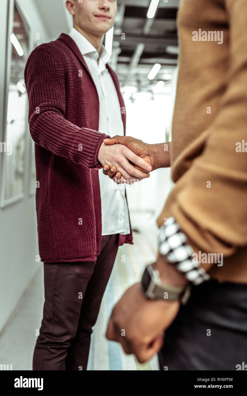 Stylish guys greeting each other at work while shaking hands Stock Photo