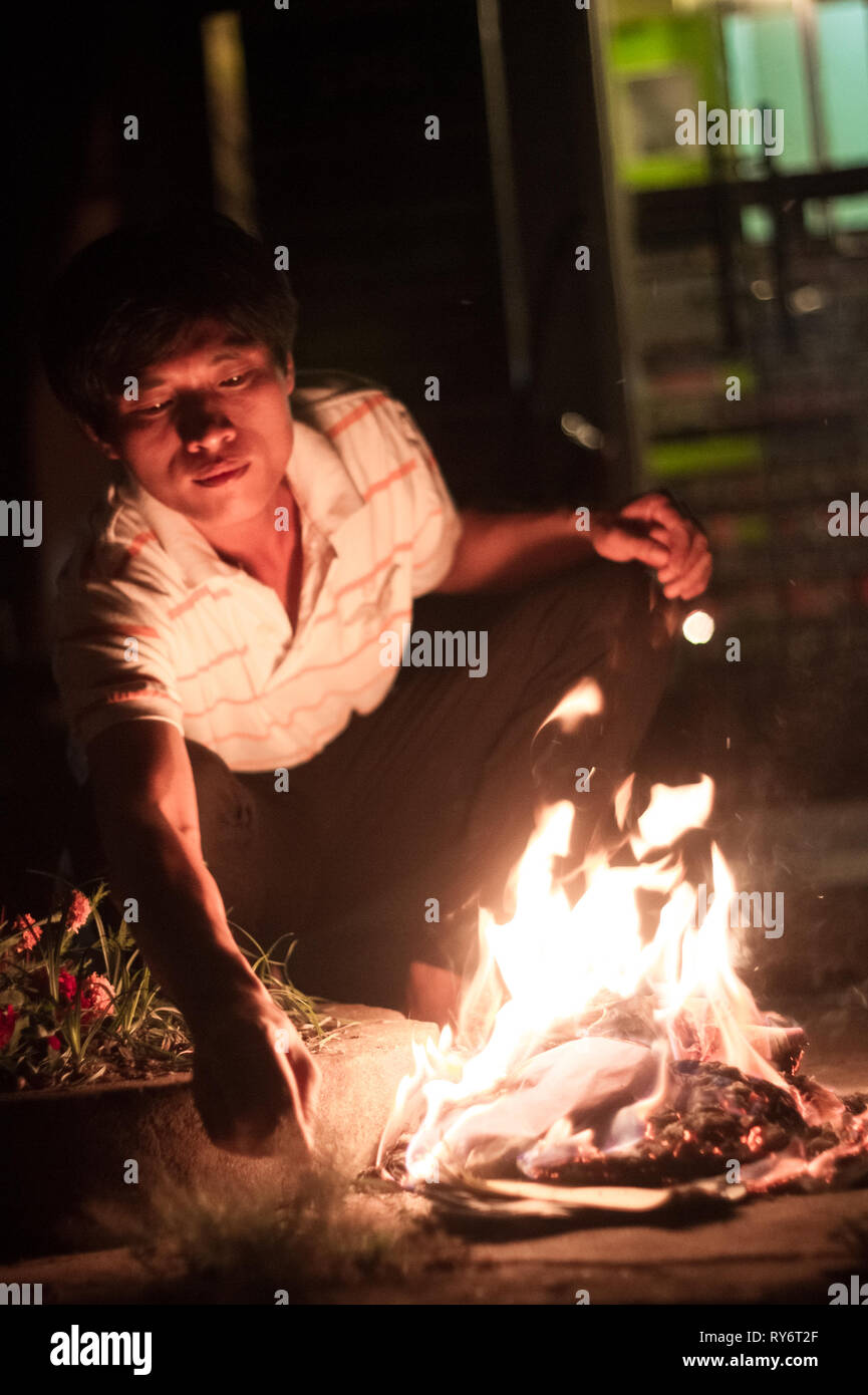 Man burning offerings for Ancestors at Mid Autumn Festival - Hoi An, Vietnam Stock Photo