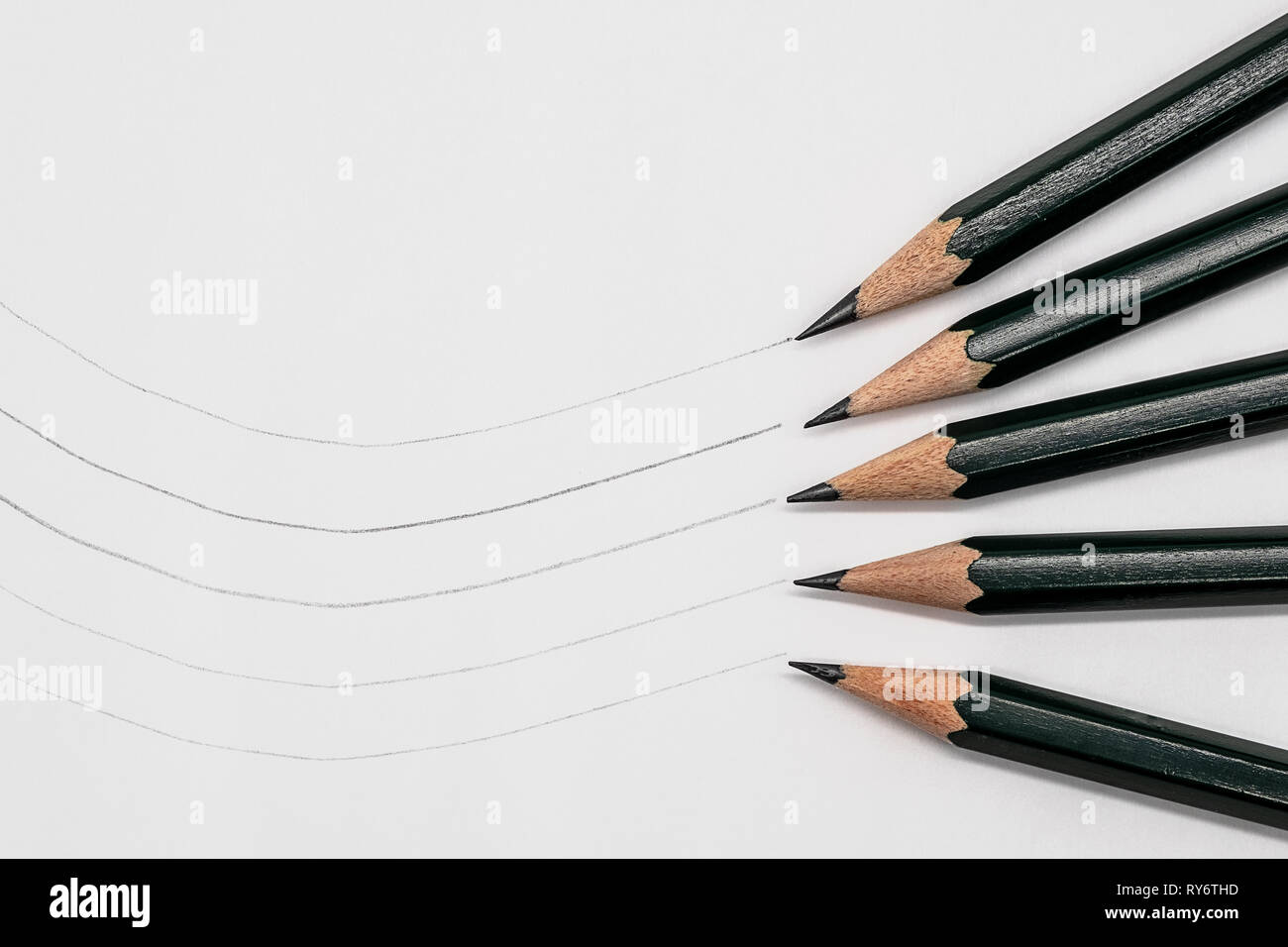 5 artist pencils lying on white paper, example line thickness Stock Photo