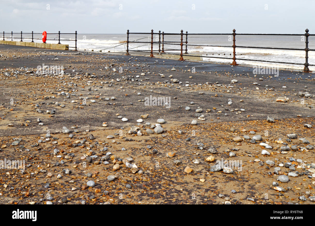 A view of the west promenade covered in stones thrown up by high seas on the North Norfolk coast at Cromer, Norfolk, England, United Kingdom, Europe. Stock Photo