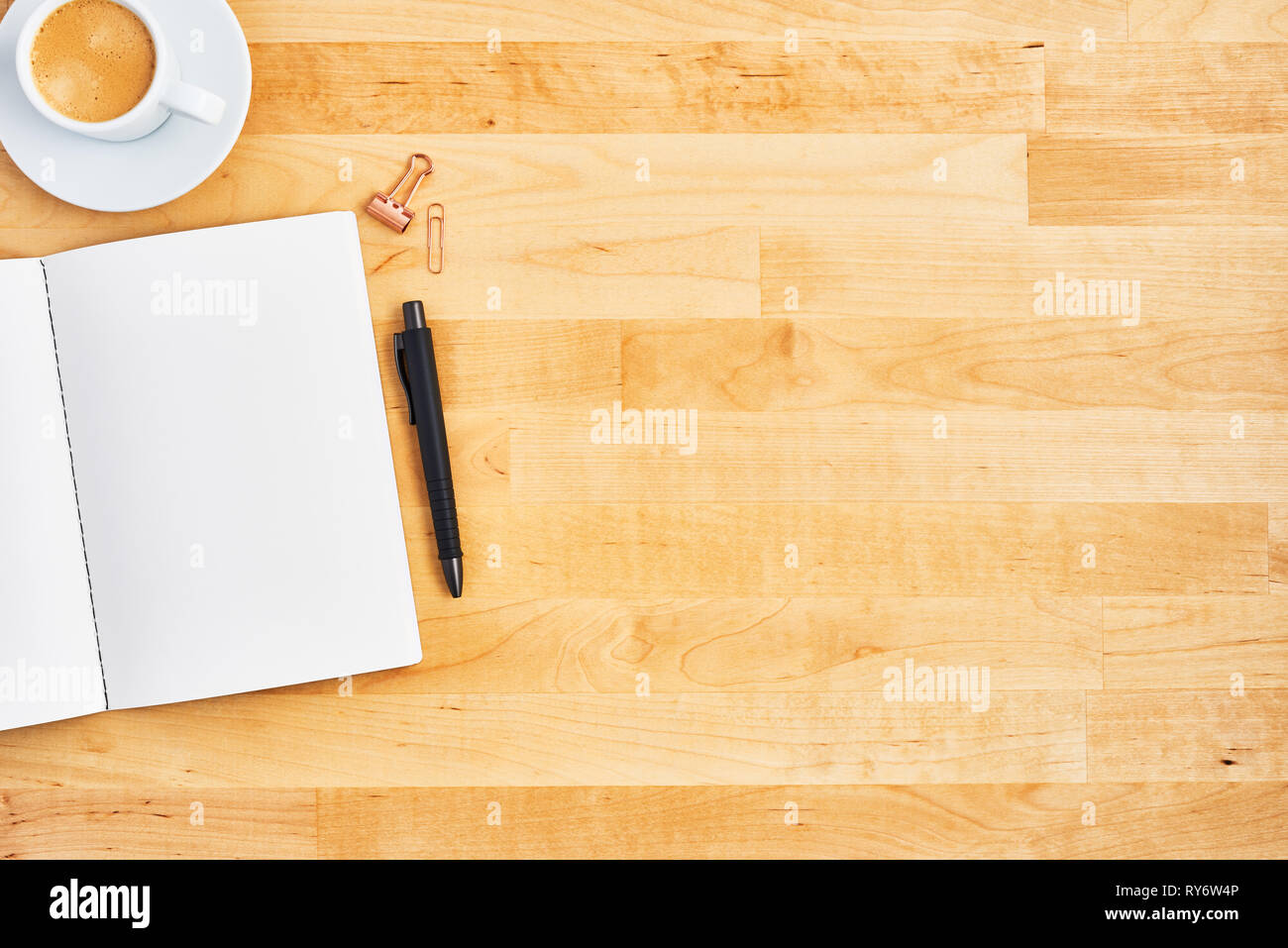 Wood office desk table with blank notebook, pen and cup of coffee or espresso. Top view. Copy space for text. Flat lay. Stock Photo