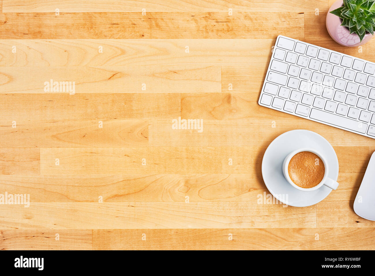 Cup of coffee or espresso with keyboard, mouse and plant on yellow wooden table. Office desktop concept. Top view. Copy space for text. Flat lay. Stock Photo