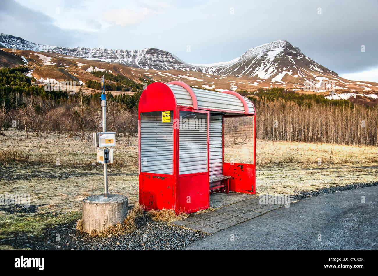 Mossfellsbaer, Iceland, February 28, 2019: a red public bus shelter catches the last rays of the sun in a beautiful mountain landscape near Mount Esja Stock Photo