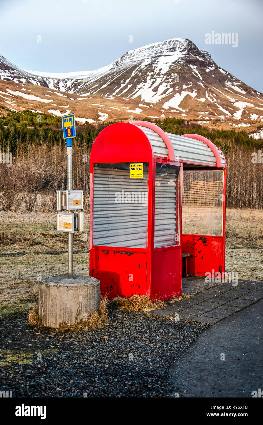Mossfellsbaer, Iceland, February 28, 2019: red shelter at a busstop with a partly snow-covered mountain in the background Stock Photo