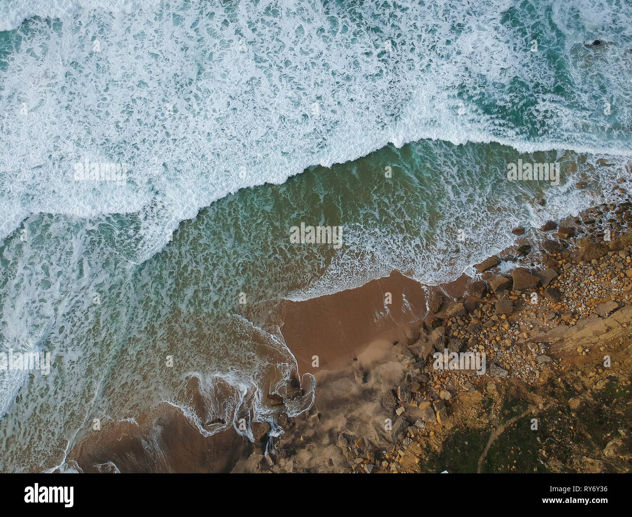 Aerial view to ocean waves and rocks in a beach. Blue water background ...