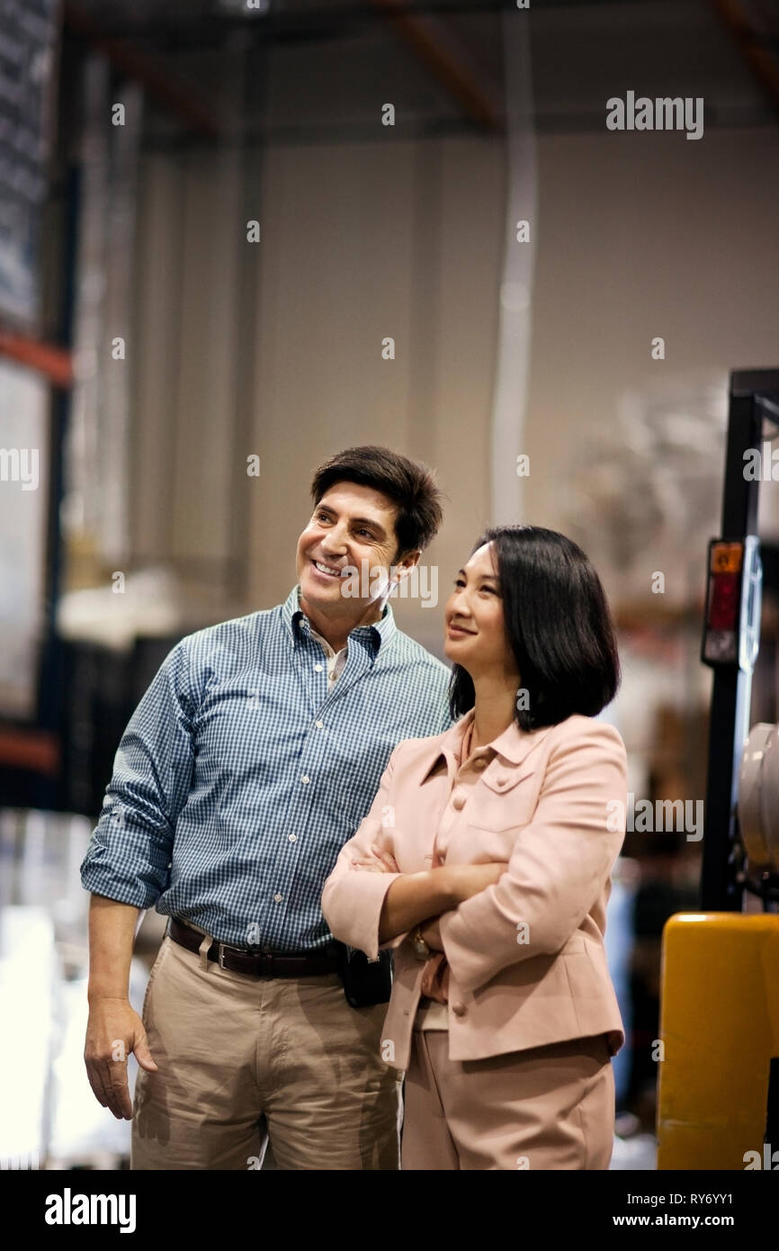 Two smiling colleagues discussing work in a warehouse. Stock Photo
