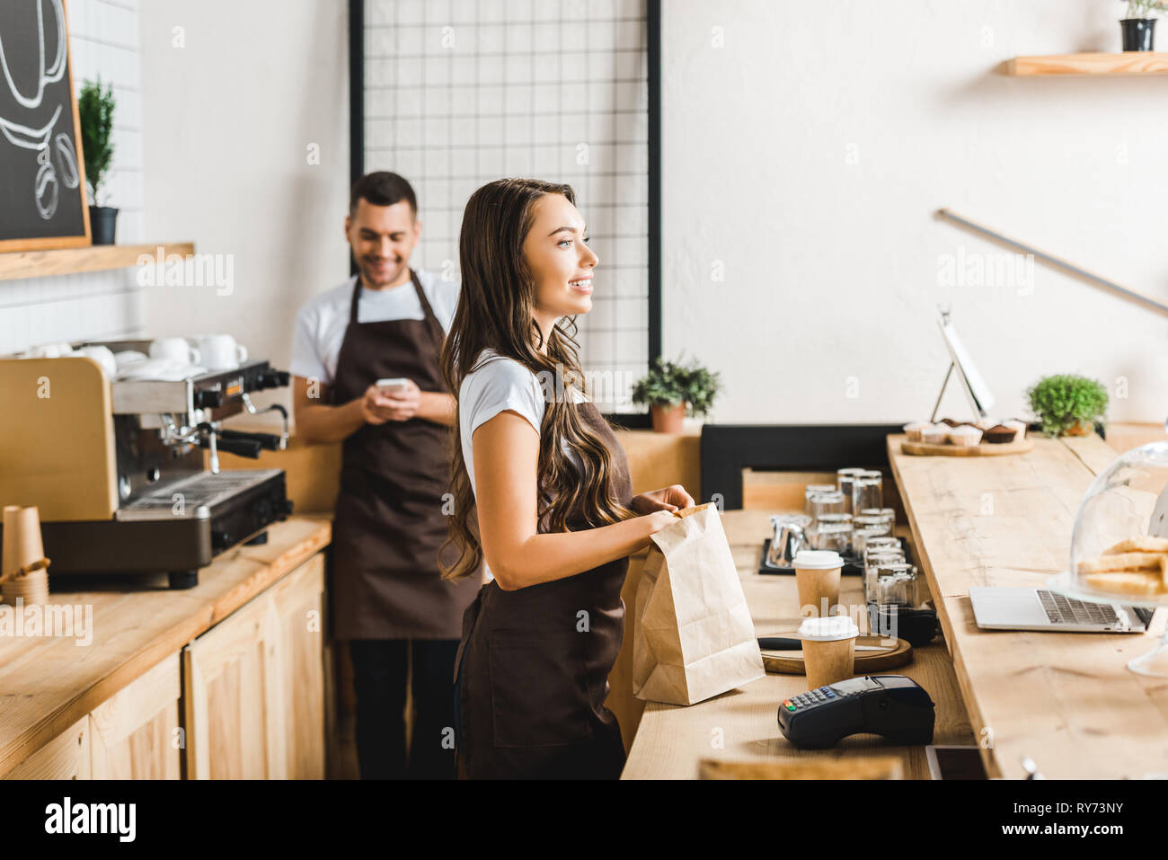 Selective Focus Of Attractive Cashier With Paper Bag And Barista