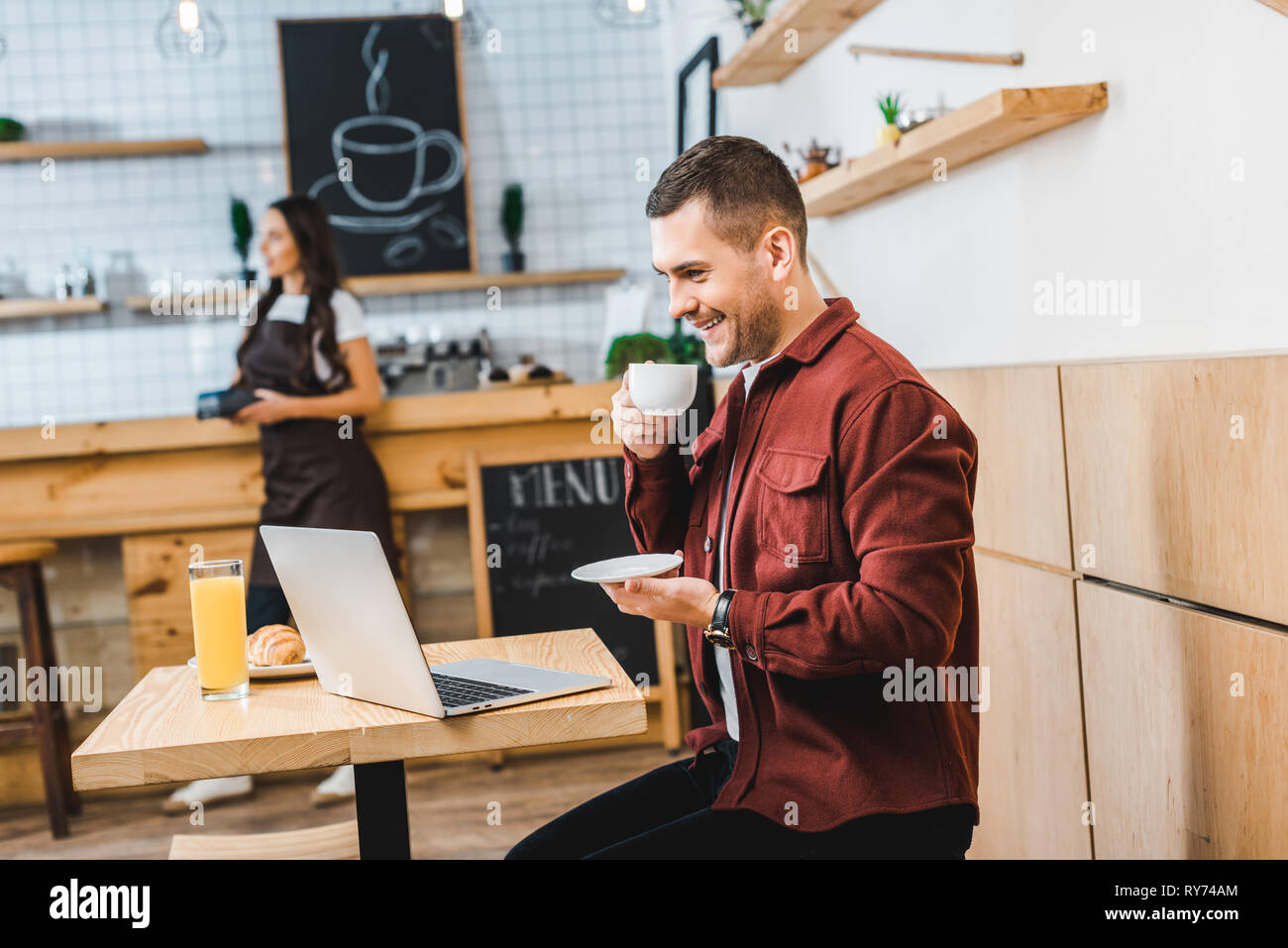 selective focus of handsome freelancer sitting at table with laptop and ...