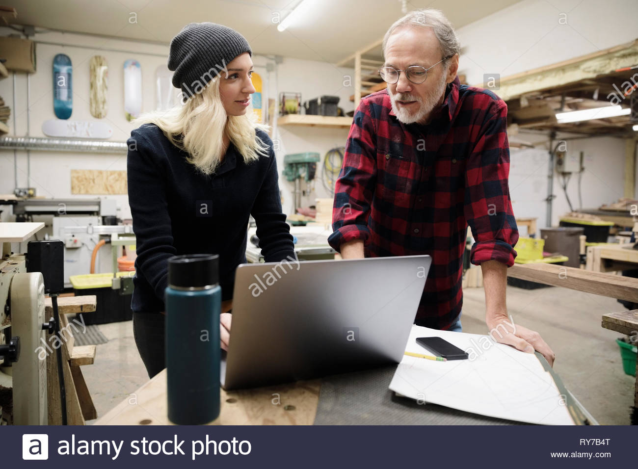 Father and daughter using laptop in workshop Stock Photo