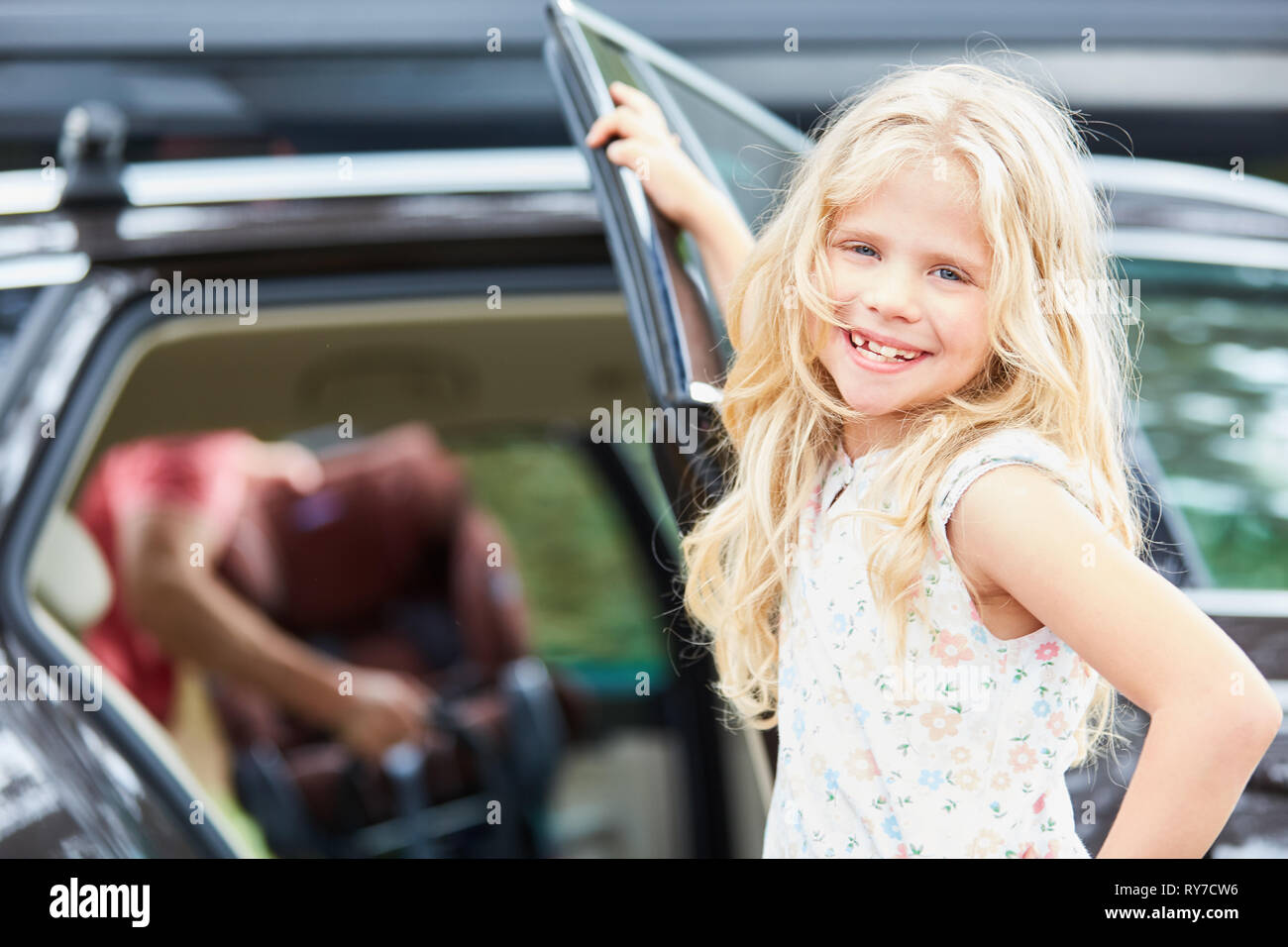 Happy girl at the car is looking forward to the trip on the summer vacation Stock Photo