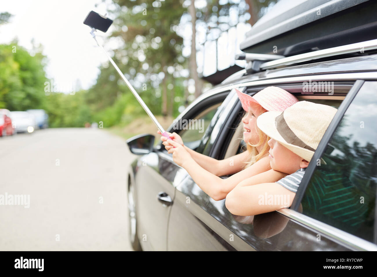 Two kids in the car take a selfie with the selfie stick on the car ride