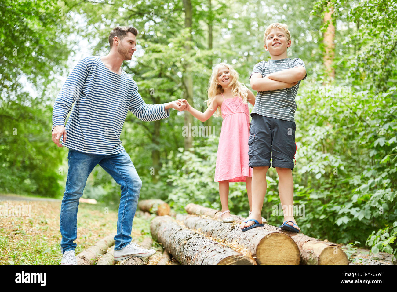 Father and children on a nature trip climb on tree trunks Stock Photo ...