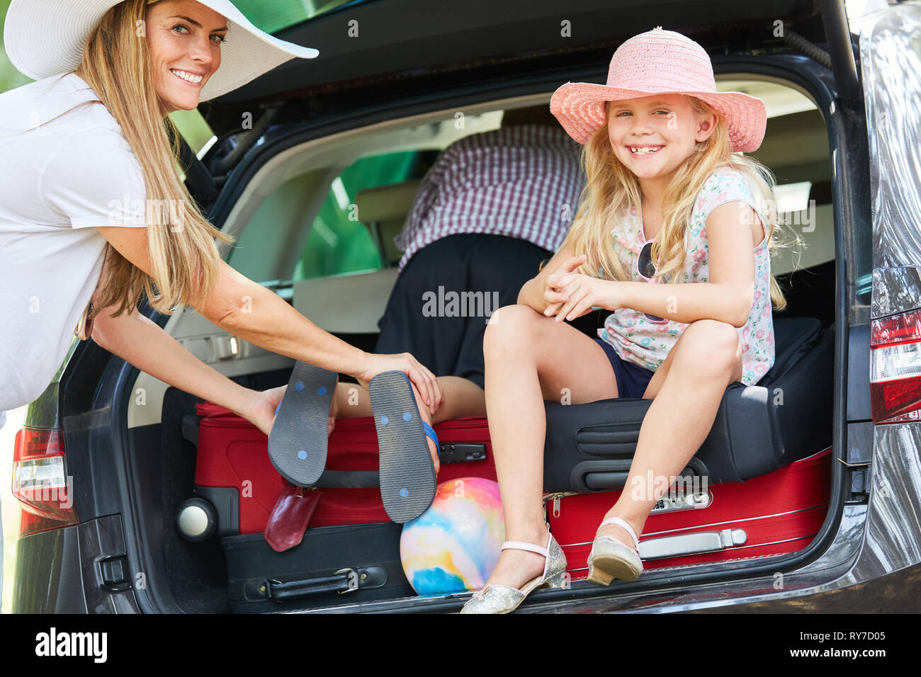 Mother and children with luggage in the car in the trunk just before the holiday trip Stock Photo