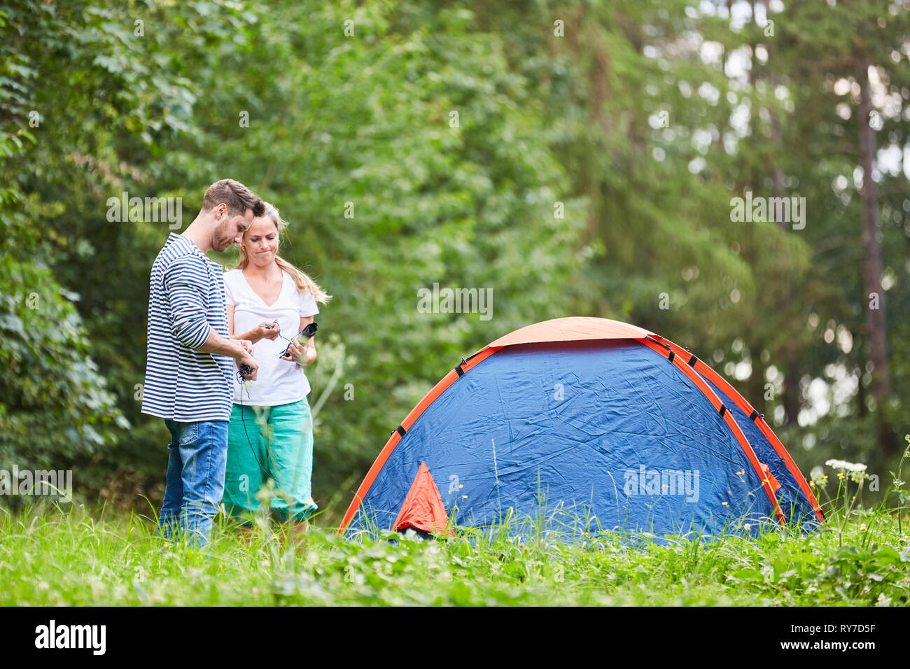 Couple in front of the tent while camping on a meadow in the outdoor ...
