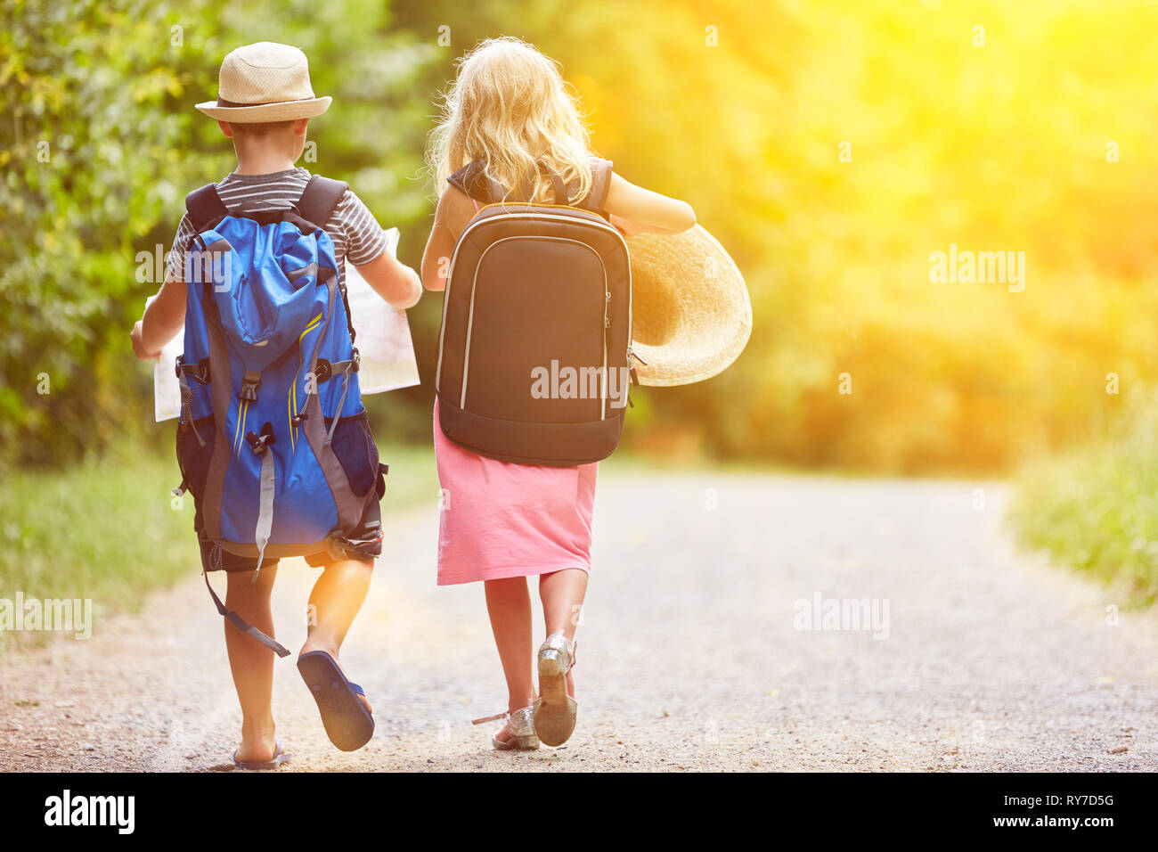 Two siblings on hike in summer in nature with backpack Stock Photo