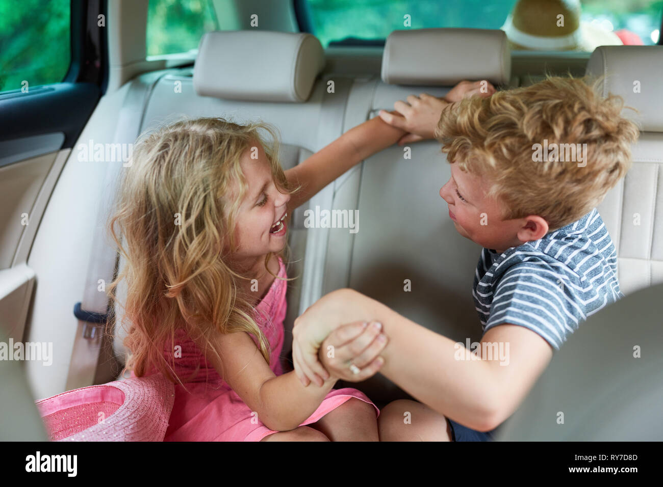 Two siblings argue and fight in the car in the backseat Stock Photo