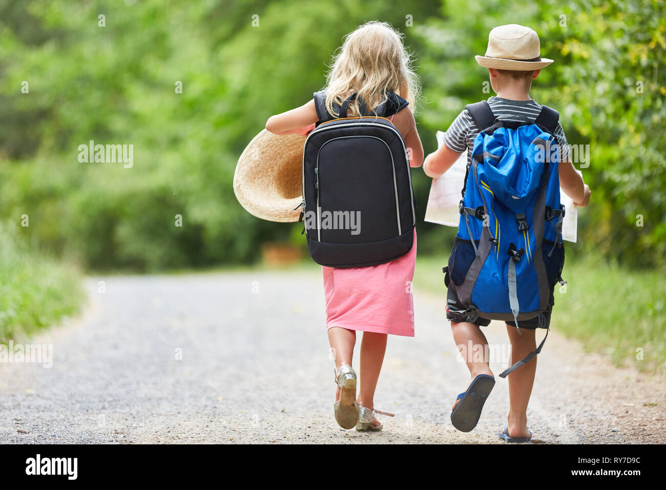 Two kids go hiking together in nature with backpack and map Stock Photo