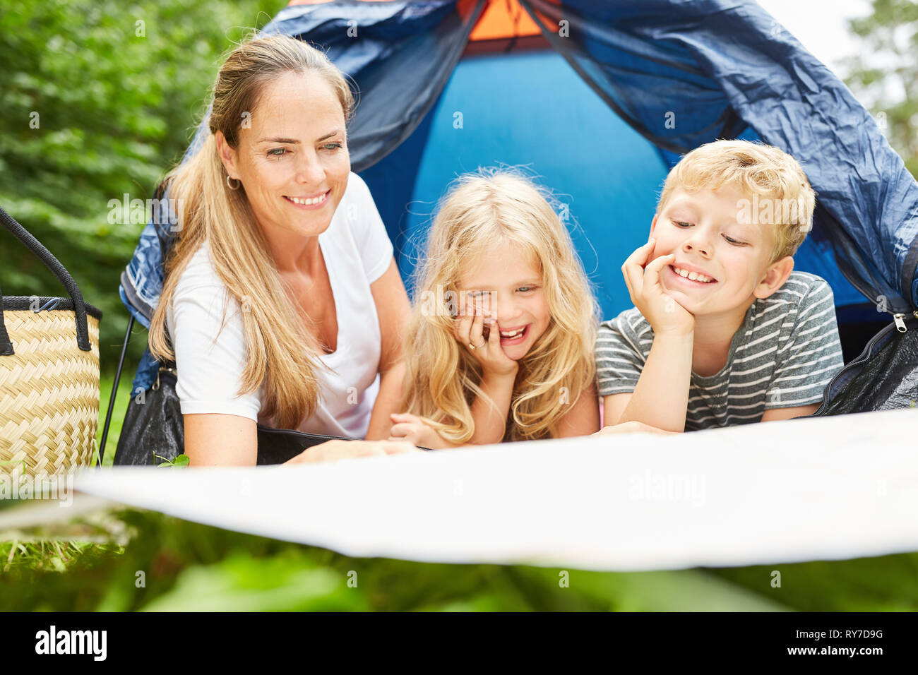 Mother and two children camping in front of the tent look at a map Stock Photo