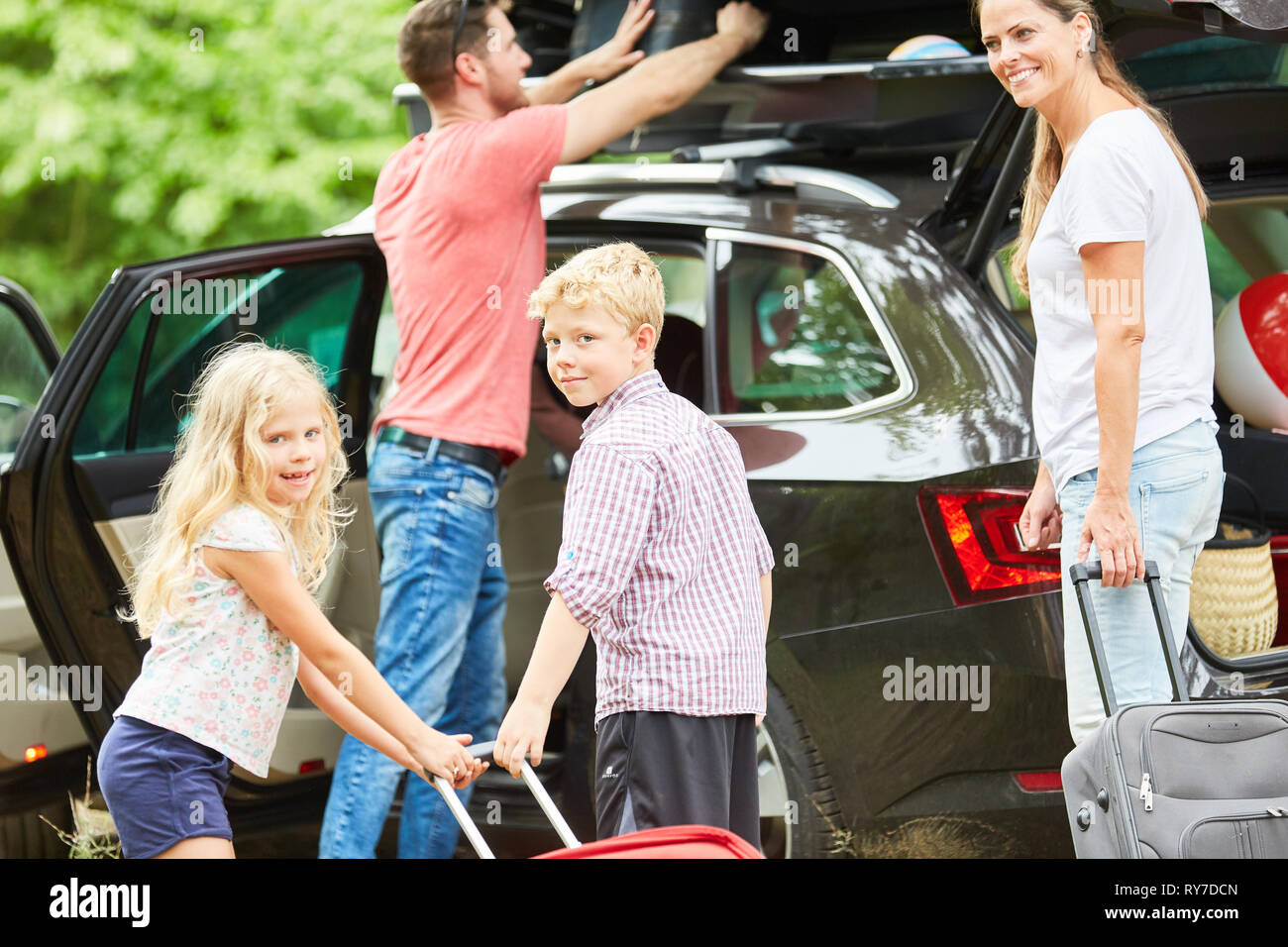 Family and children together at the suitcase packing at the car before the vacation trip Stock Photo