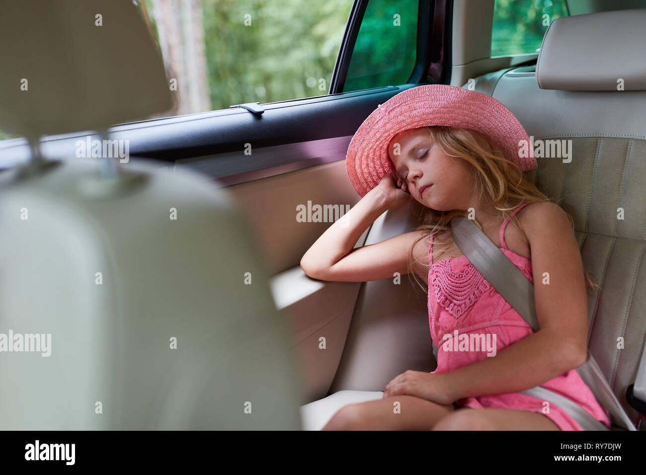 Girl peacefully sleeps on back seat in the car on the journey into summer vacation Stock Photo
